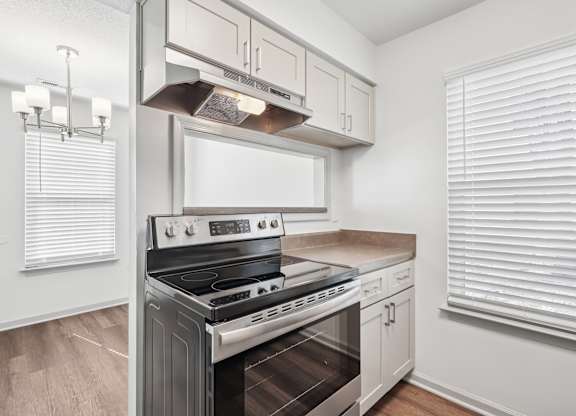 A modern kitchen with a stainless steel oven and white cabinets.