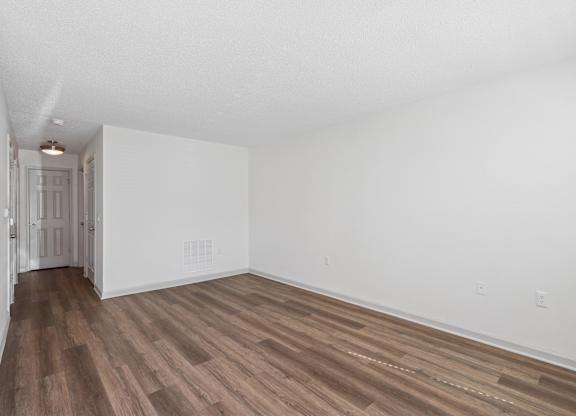 A room with wooden flooring and white walls.
