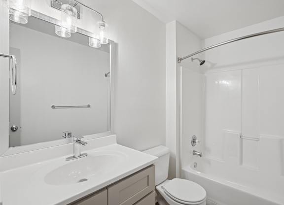 A white bathroom with a toilet, sink, and bathtub.