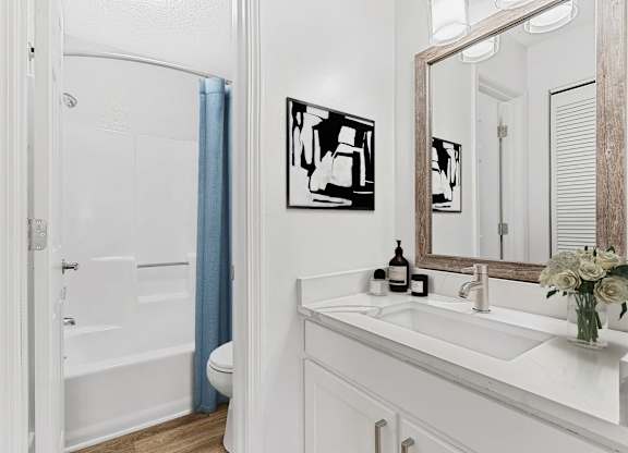 A white bathroom with a white sink and a white toilet. at Woodlyn on the Green Apartment Homes, Cary, 27513