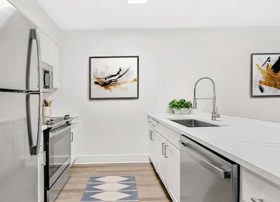 A modern kitchen with a white fridge, a sink, and a dishwasher. at Woodlyn on the Green Apartment Homes, Cary, NC