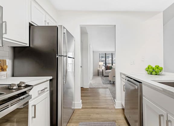A kitchen with a black refrigerator and white cabinets. at Woodlyn on the Green Apartment Homes, Cary, NC