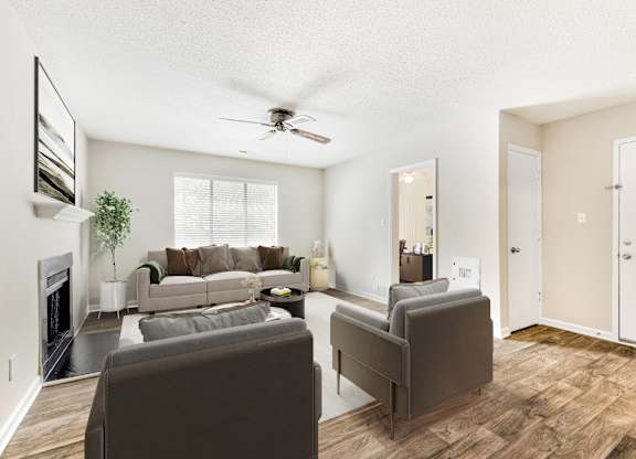 A living room with a grey couch and a fireplace. at Woodlyn on the Green Apartment Homes, Cary, 27513