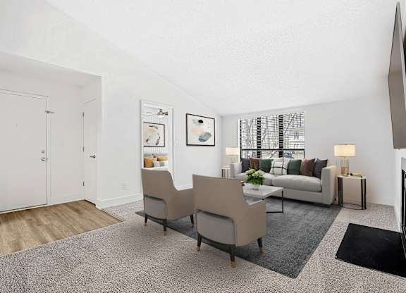 A living room with a grey carpet and a white sofa. at Woodlyn on the Green Apartment Homes, Cary, NC, 27513