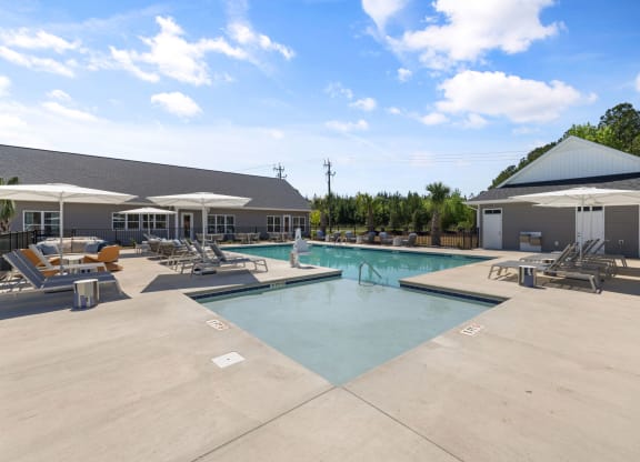 a swimming pool with chairs and umbrellas next to a building