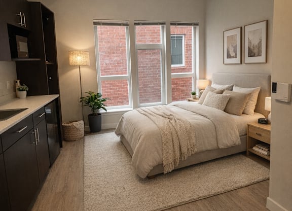 A bedroom with a bed, nightstand, and a window with a view of a brick building outside.