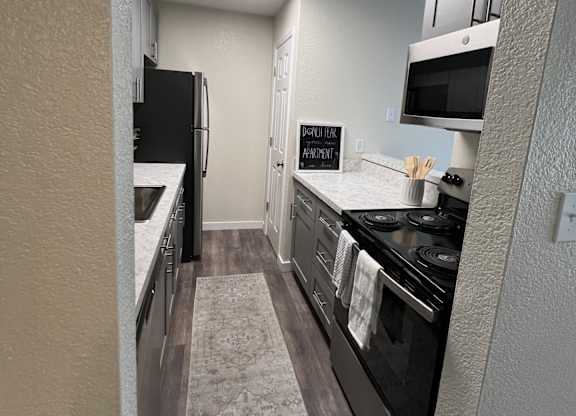 A kitchen with a black refrigerator, stove, and a rug on the floor.