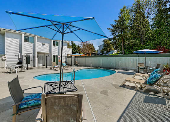 Cool Swimming Pool with Lounge Chairs and Shaded Bistro Table Set at Campo Basso Apartment Homes, Washington, 98087