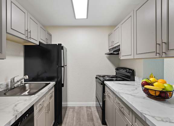 View into Kitchen with Updated Flooring, Grey Cabinets, and Marble-Look Countertops at Campo Basso Apartment Homes, Lynnwood