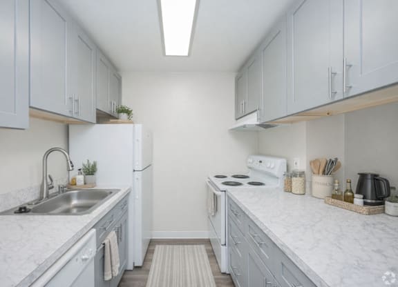 A kitchen with white cabinets and marble countertops.