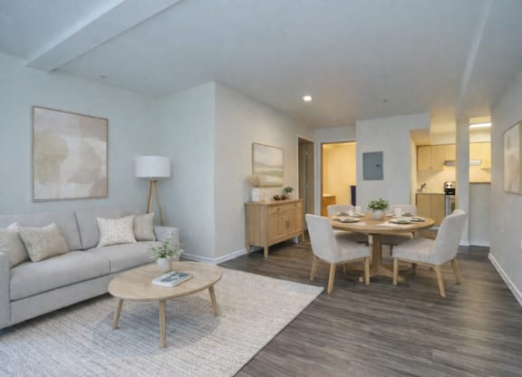 A living room with a grey couch, a wooden coffee table, and a dining table with chairs.