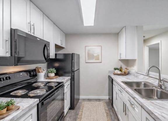 A modern kitchen with black appliances and white cabinets.