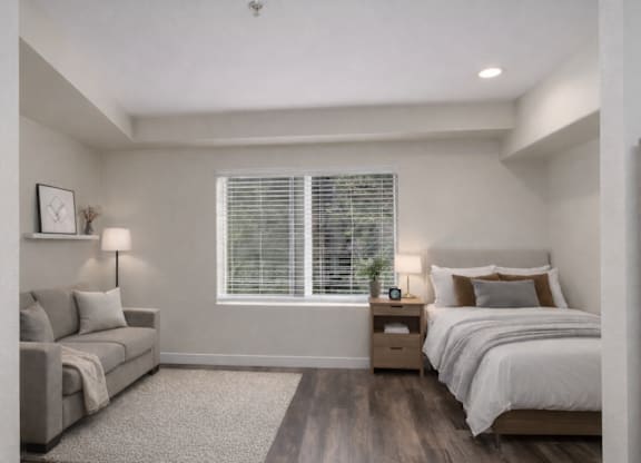 A bedroom with a bed, nightstand, and couch.