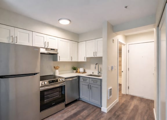 A modern kitchen with stainless steel appliances and wooden floors.