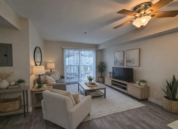 A living room with a ceiling fan and a flat screen TV.