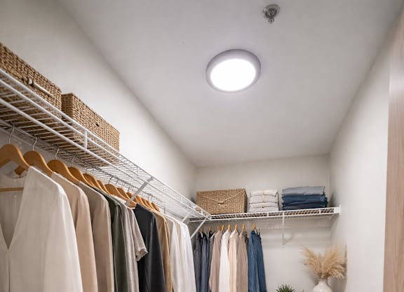 A white closet with clothes and shoes.