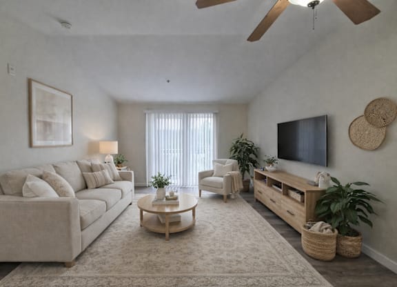 A living room with a beige sofa, a wooden coffee table, a flat-screen TV, and a ceiling fan.
