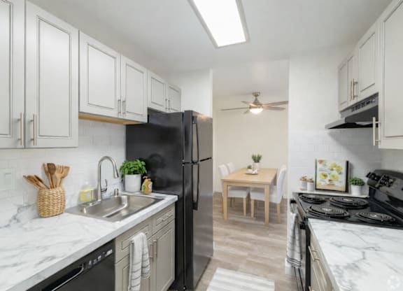 A kitchen with black appliances and white cabinets.
