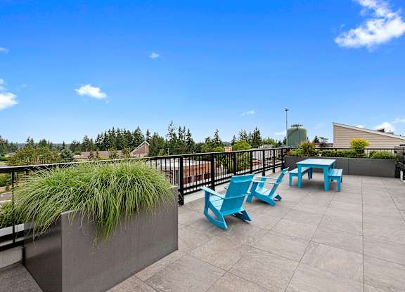 a seating area on the rooftop resident lounge with blue chairs and a table at Arabella Apartment Homes, Shoreline