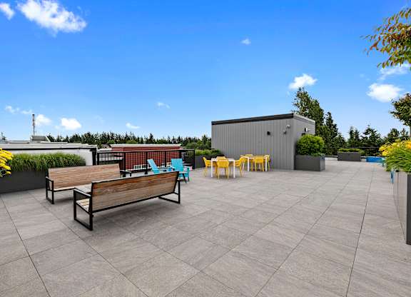 Resident Rooftop Lounge with yellow flowers and benches, chairs, and firepit to lounge by while enjoying rooftop views at Arabella Apartment Homes, Shoreline, WA