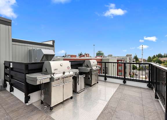 Resident Lounge Area with two barbecue grills and a blue sky in the background at Arabella Apartment Homes, Shoreline, WA