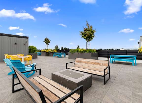 Rooftop Lounge Area with Benches, Blue Adirondack Chairs, and Cozy Firepit at Arabella Apartment Homes, Shoreline, Washington 98155