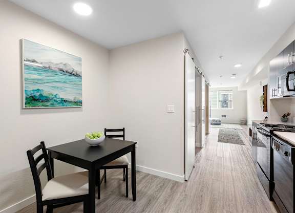 a dining area with a table and chairs and a kitchen in the background at Arabella Apartment Homes, Shoreline, WA