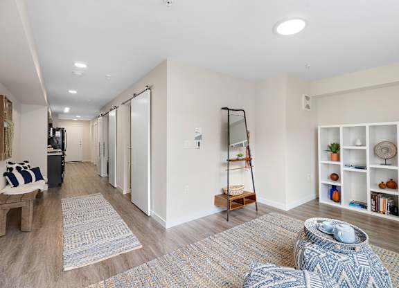 Apartment Living Area with Plank Flooring and cozy rugs, white bookshelf, and recessed lighting at Arabella Apartment Homes, Washington