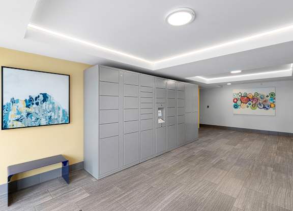a row of package lockers with a painting on the yellow accent wall at Arabella Apartment Homes, Shoreline, 98155
