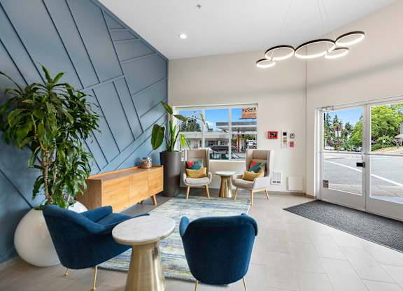 Lobby Area with blue chairs, textured dark blue accent wall, and a wooden desk with a plant in the corner at Arabella Apartment Homes, Shoreline