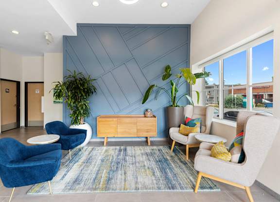Cozy Lobby Seating Area with blue chairs and a yellow table in front of a textured blue accent wall at Arabella Apartment Homes, WA 98155