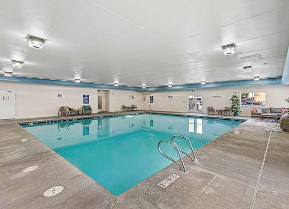 a swimming pool with chairs and tables around it  at Camelot Apartment Homes, Everett, WA, 98204