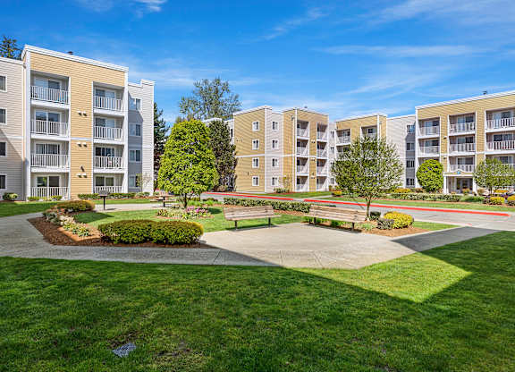 an exterior view of an apartment complex with green grass and trees  at Camelot Apartment Homes, Everett, WA, 98204