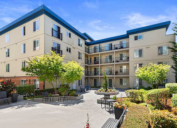 beautiful courtyard with paved area lined with plants and bushes at Guinevere Apartment Homes, Seattle, WA