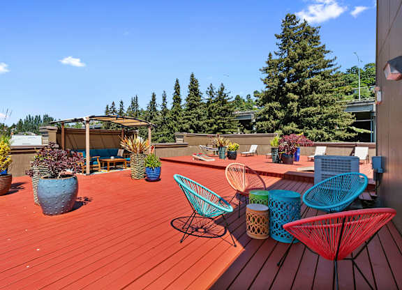 a roof deck with chairs and potted plants at Illumina Apartment Homes, Seattle, 98102