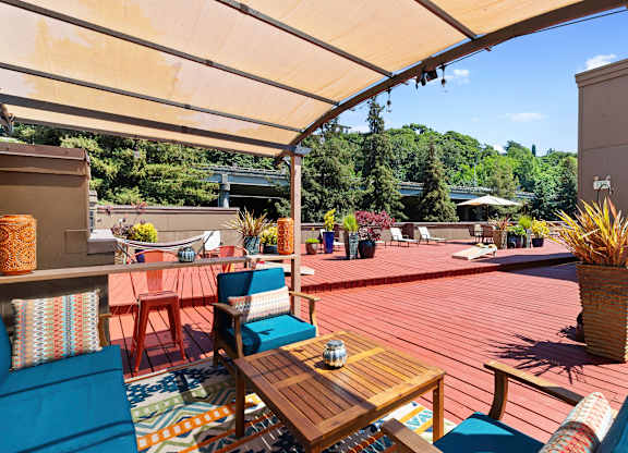 Shaded Wooden Deck Area with blue chairs and a wooden table for Relaxing at Illumina Apartment Homes, WA 98102