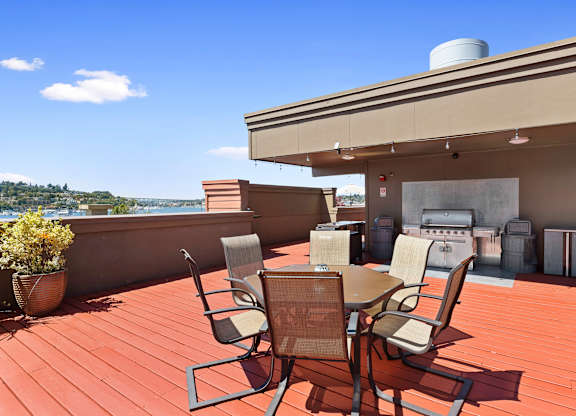 Rooftop patio area with a table and lounge chairs and a grill at Illumina Apartment Homes, WA 98102