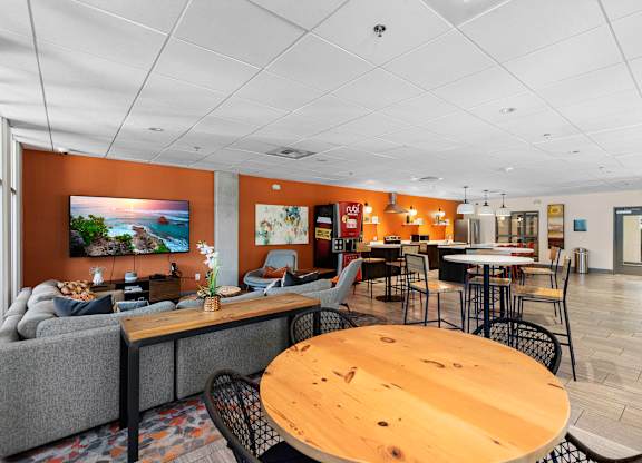 a lounge area with tables and chairs and a resident community kitchen in the background at Sedona Apartments, Seattle, Washington