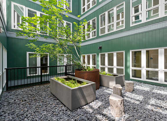 an outdoor courtyard with large concrete planters and stools  t Sedona Apartments, Seattle, 98115