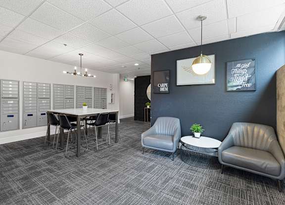 Cozy Lobby Area with a table and chairs and convenient mailboxes on the wall at Villaggio Apartment Homes, Tacoma, 98402