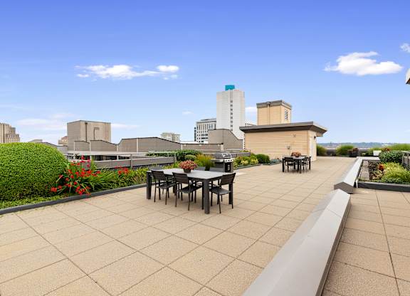 Resident Rooftop Lounge with tables and chairs and a view of the city at Villaggio Apartment Homes, Tacoma, Washington 98402