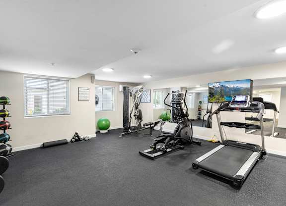 a gym with exercise equipment and a flat screen tv at West Mall Place Apartment Homes, Everett, WA