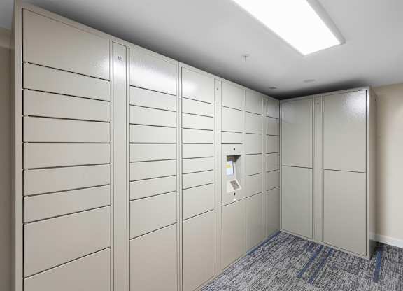 White Package Receiving Lockers in a room with a gray carpet at West Mall Place Apartment Homes, Everett