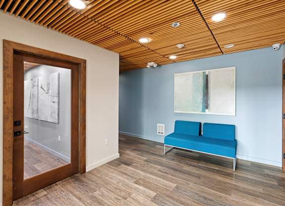 Resident Lobby Area with a blue couch and a large painting on the wall at Excalibur Apartment Homes, Washington, 98004