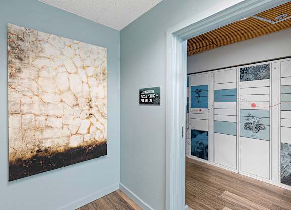 Hallway with a Painting that Leads to the Package Receiving Lockers at Excalibur Apartment Homes, WA 98004