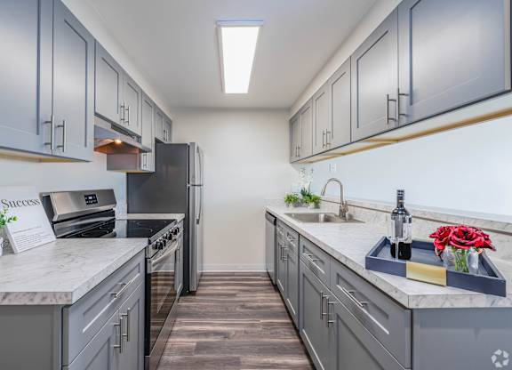 A kitchen with grey cabinets and a white countertop. at Hill Crest Apartment Homes, Seattle, 98126