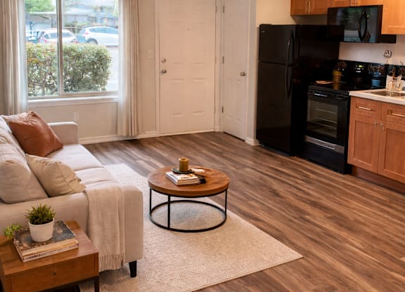 A kitchen with a black refrigerator and wooden floors.