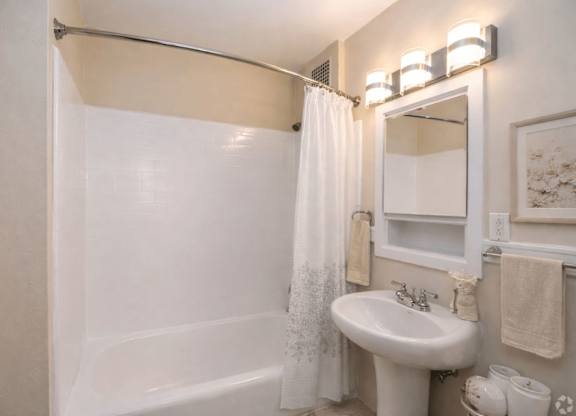 A white bathroom with a white sink and a white bathtub.