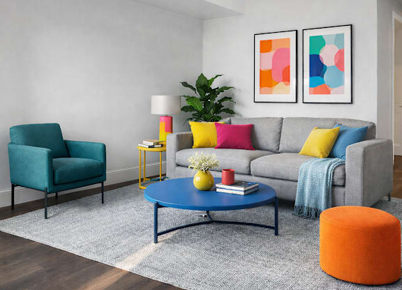 A living room with a grey couch, a blue coffee table, a green chair, a yellow side table, and a potted plant.