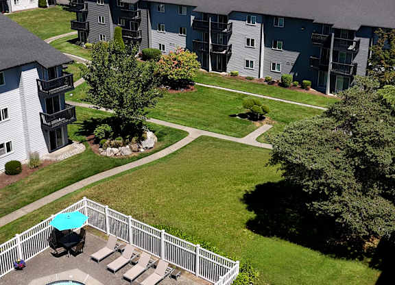 A pool with a hot tub and a white fence in front of a building.
